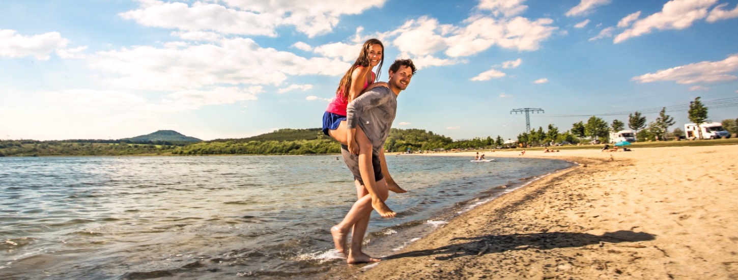Ein Pärchen watet durch das flache Wasser am Berzdorfer See